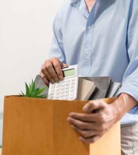 man in blue shirt packing up his desk into a box after redundancy
